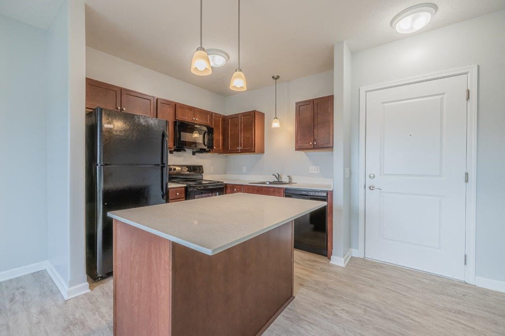 a kitchen with a large island and a black refrigerator