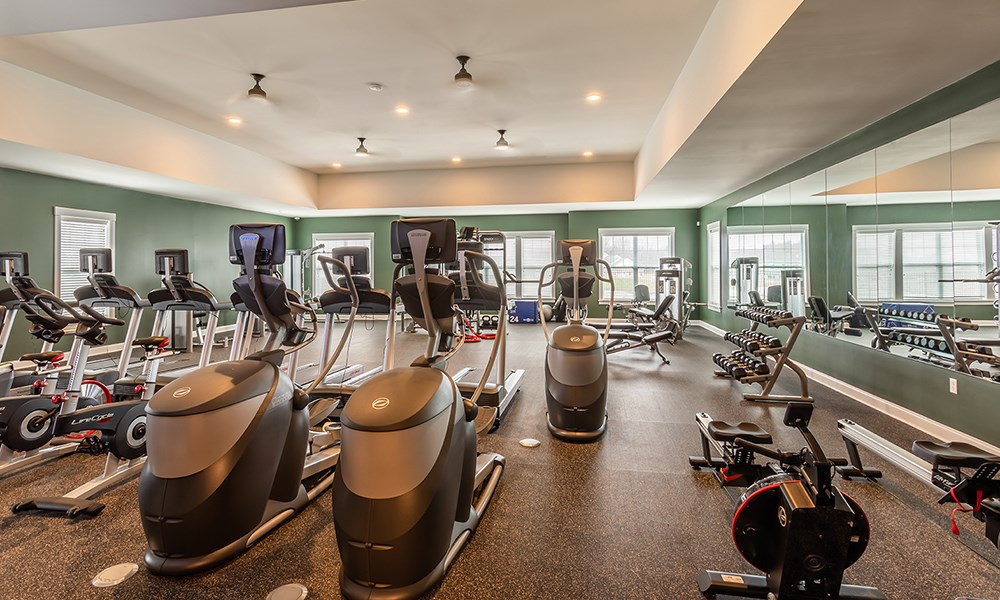 a gym with cardio equipment and weights on the floor