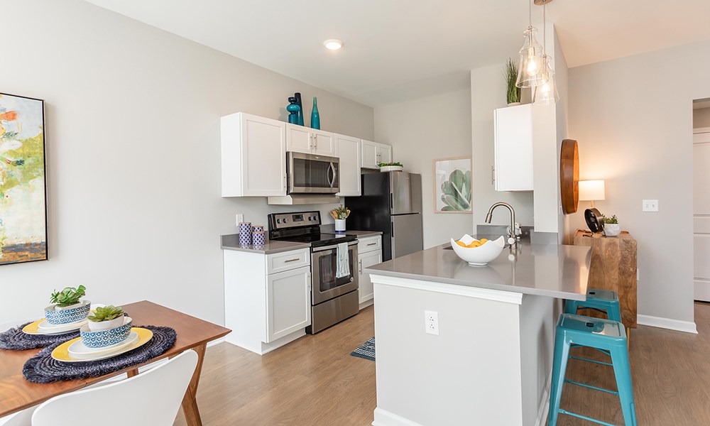 a kitchen with stainless steel appliances and a table with blue stools