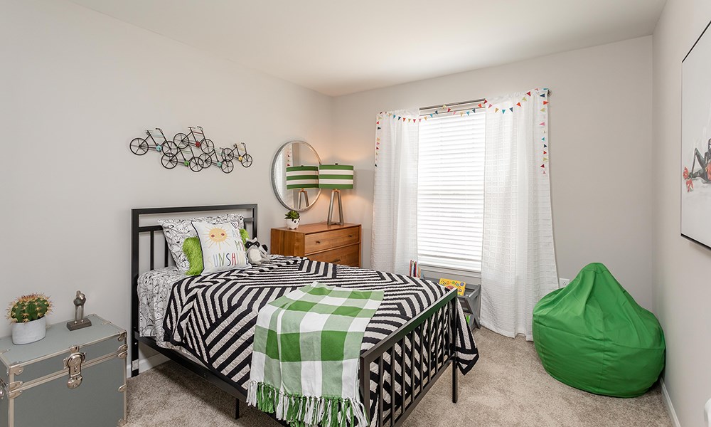 a bedroom with a bed and a green and white bedspread