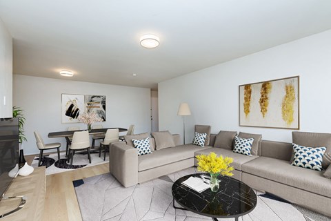 A living room with a grey couch, a coffee table, and a painting on the wall.
