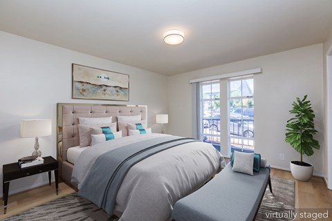 A bedroom with a large bed and a window overlooking a balcony.