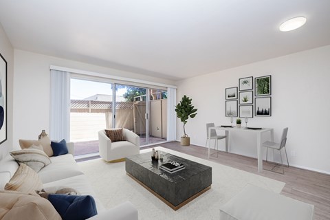 A living room with a white couch, a coffee table, and a dining table with chairs.