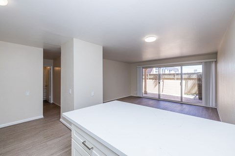 A large white kitchen with a long counter and a view of the backyard.