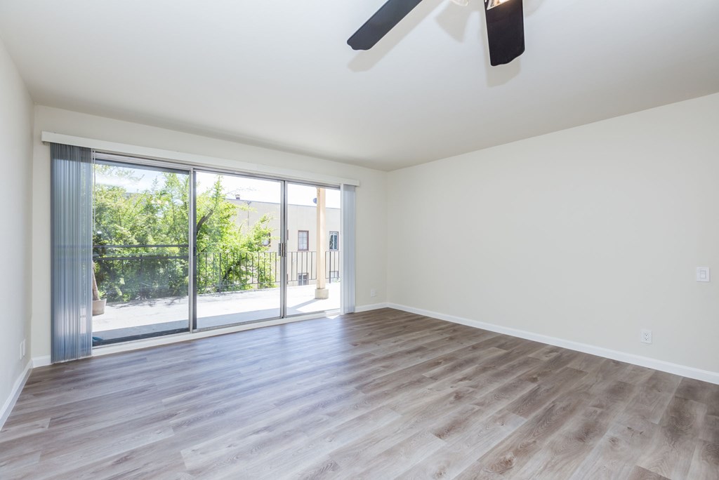 A room with a ceiling fan and sliding glass doors.