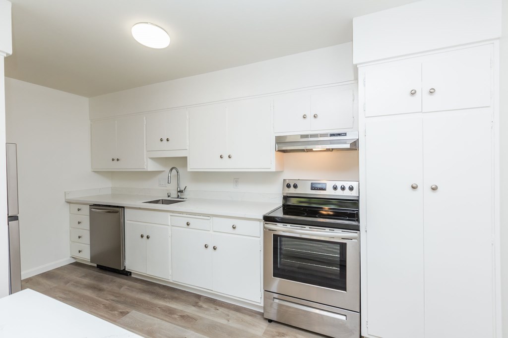A modern kitchen with white cabinets and stainless steel appliances.