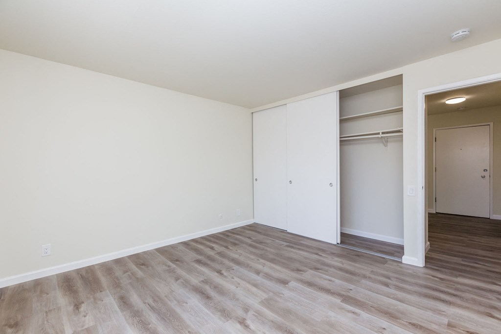 A room with a white wall and a white closet with a door.