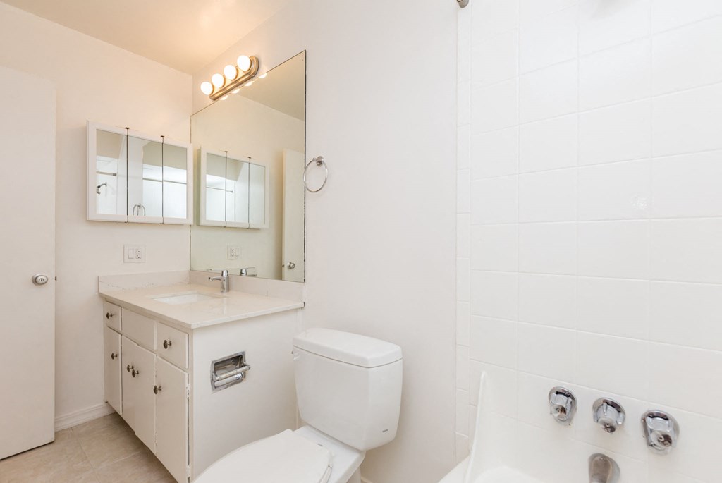 A white bathroom with a toilet, sink, and mirror.