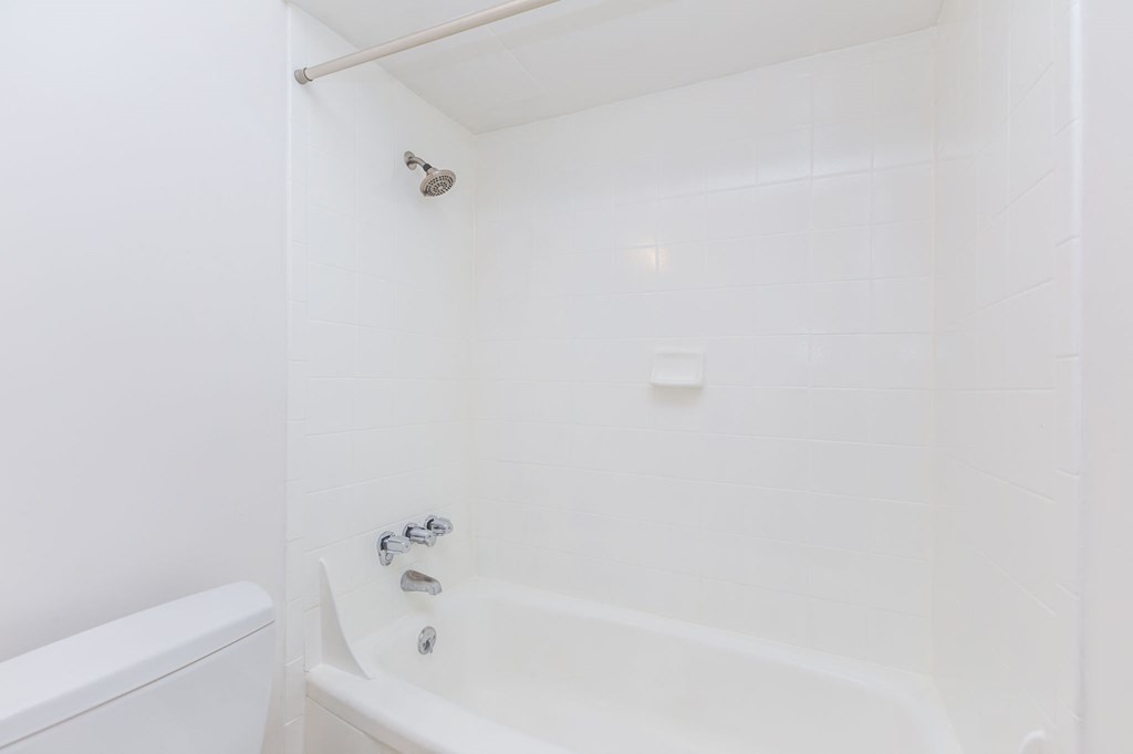 A white bathtub with a shower head and faucet.