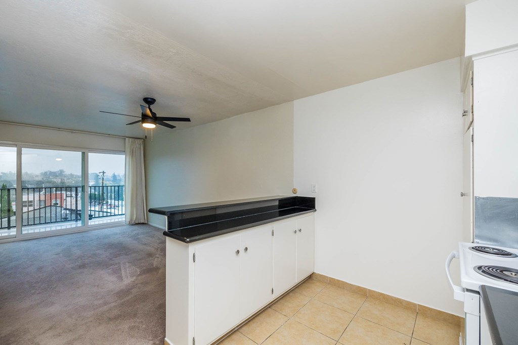 A kitchen with white cabinets and a black countertop.