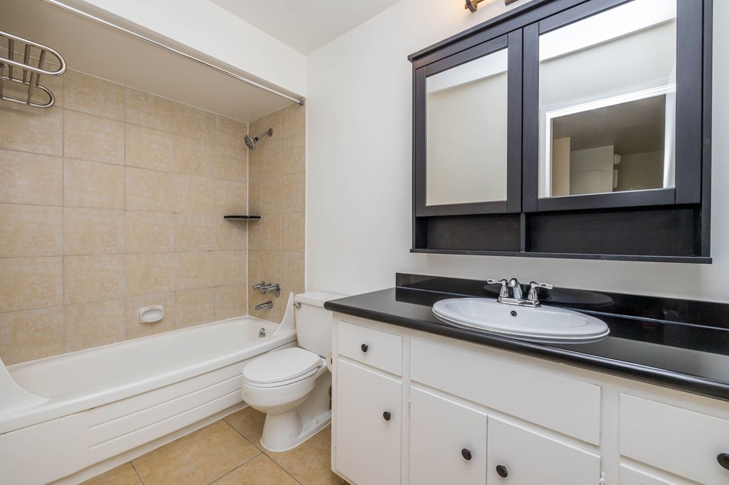 A bathroom with a white tub, sink, and toilet.
