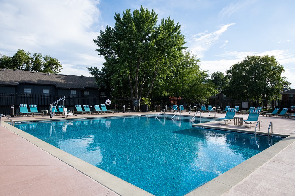 a swimming pool with chaise lounge chairs and trees in the background