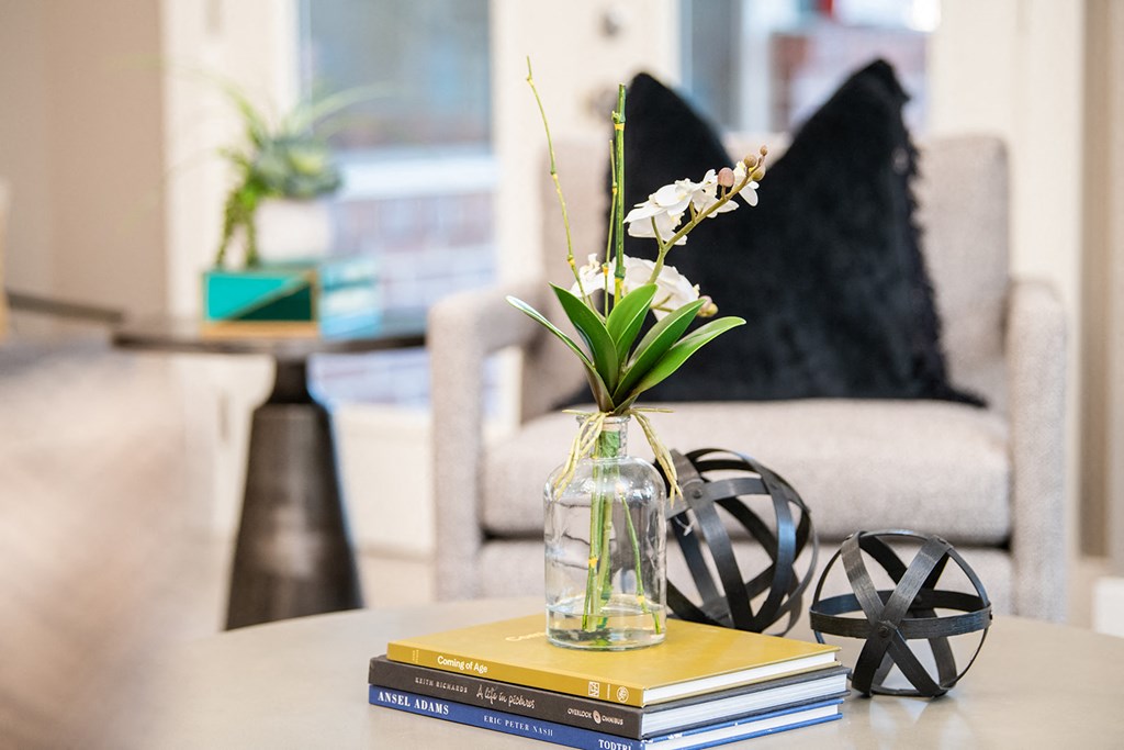 a table with a vase of flowers on top of a stack of books