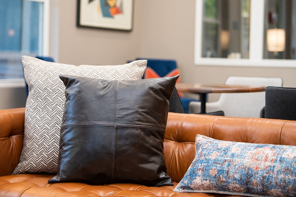 a leather couch with pillows and a coffee table in the background