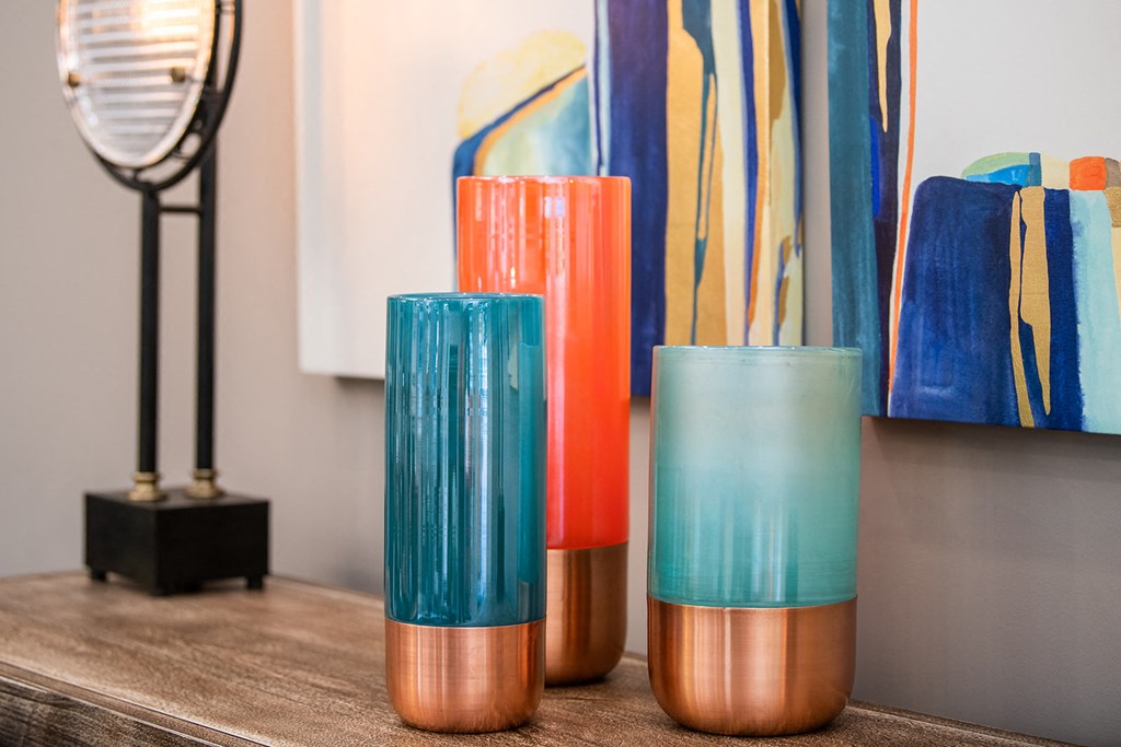 a table with three vases on it and a painting in the background