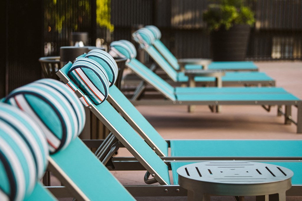 a row of blue chaise lounges with a table