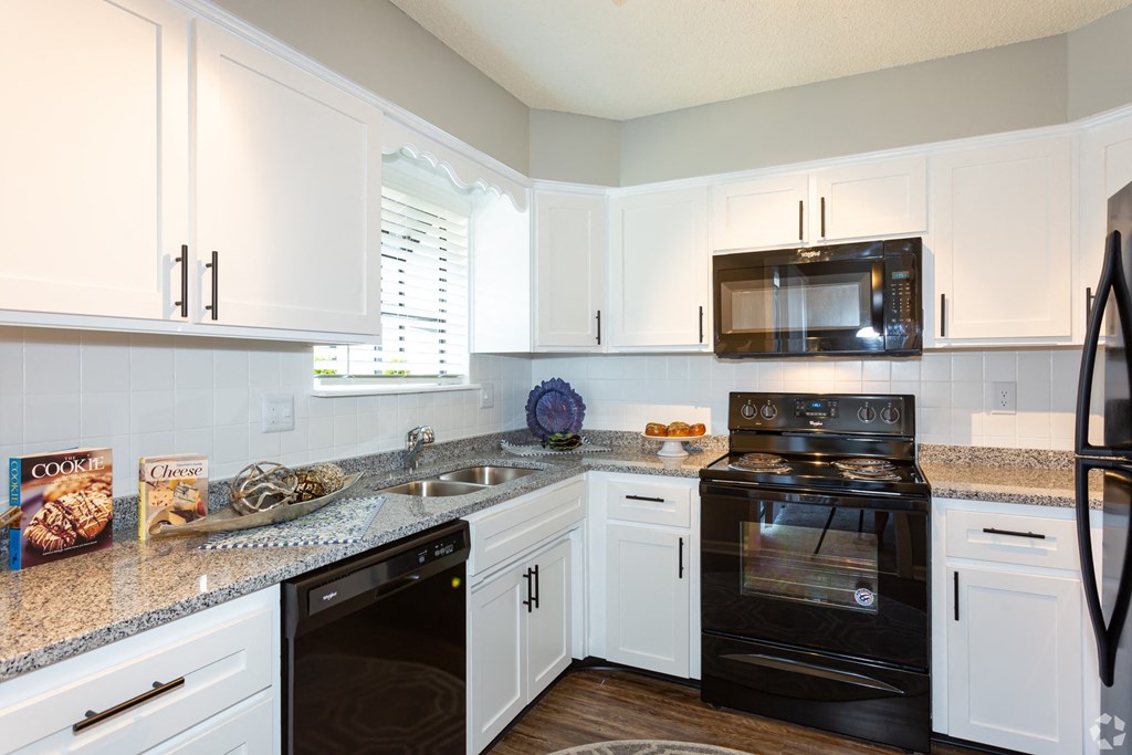 a kitchen with white cabinets and black appliances