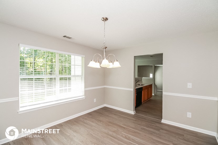 a spacious living room with a large window and wood flooring