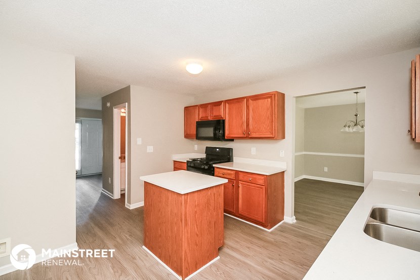 a kitchen with wooden cabinets and a white counter top and a sink