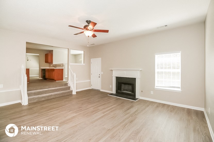 a living room with a fireplace and a ceiling fan