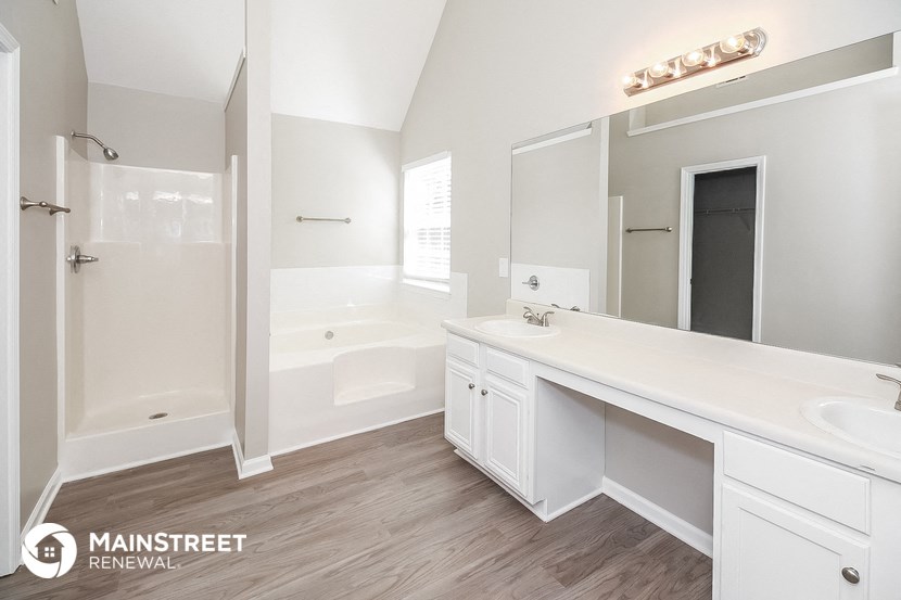 a white bathroom with a tub and a sink and a mirror