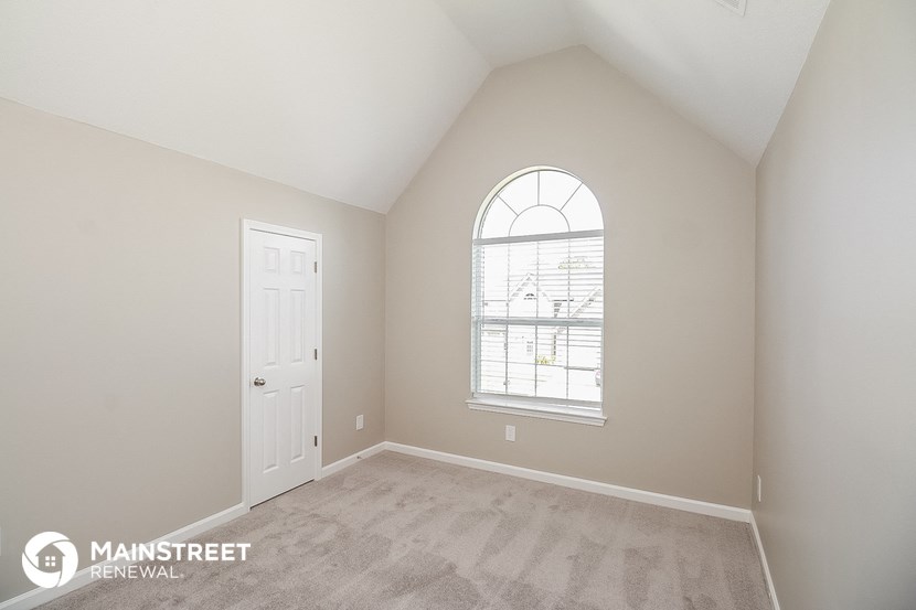 the master bedroom has a large window and carpeted flooring
