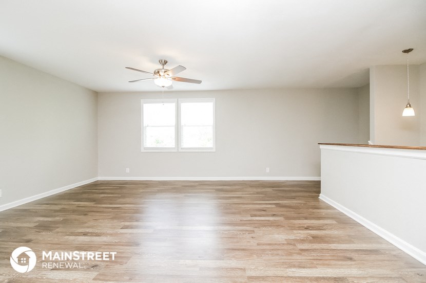 an empty living room with wood floors and a ceiling fan