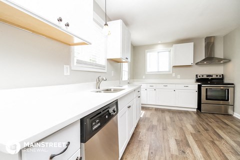 a kitchen with white cabinets and stainless steel appliances and a white counter top