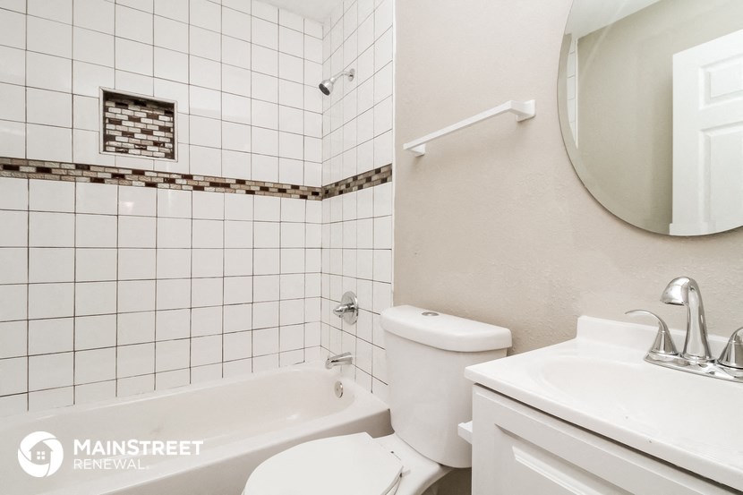 a white tiled bathroom with a toilet sink and tub