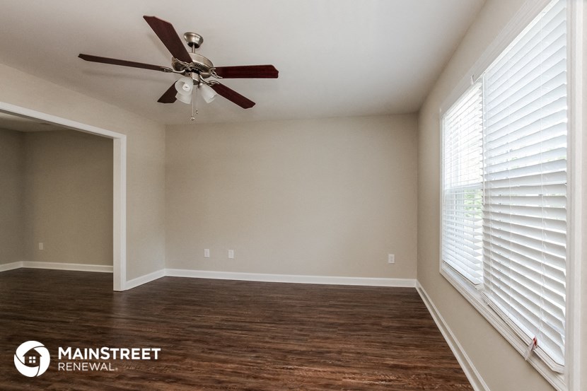 a living room with a large window and a ceiling fan