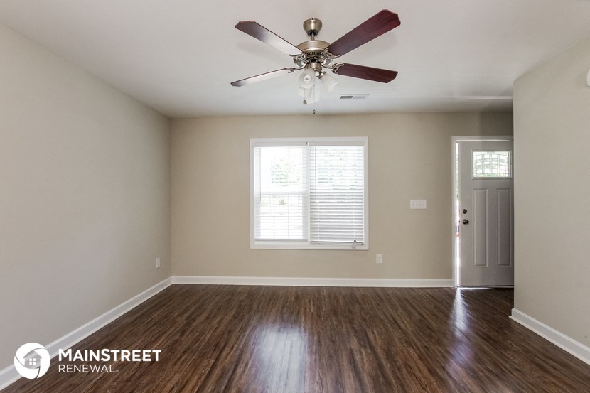 the spacious living room with ceiling fan and hardwood flooring