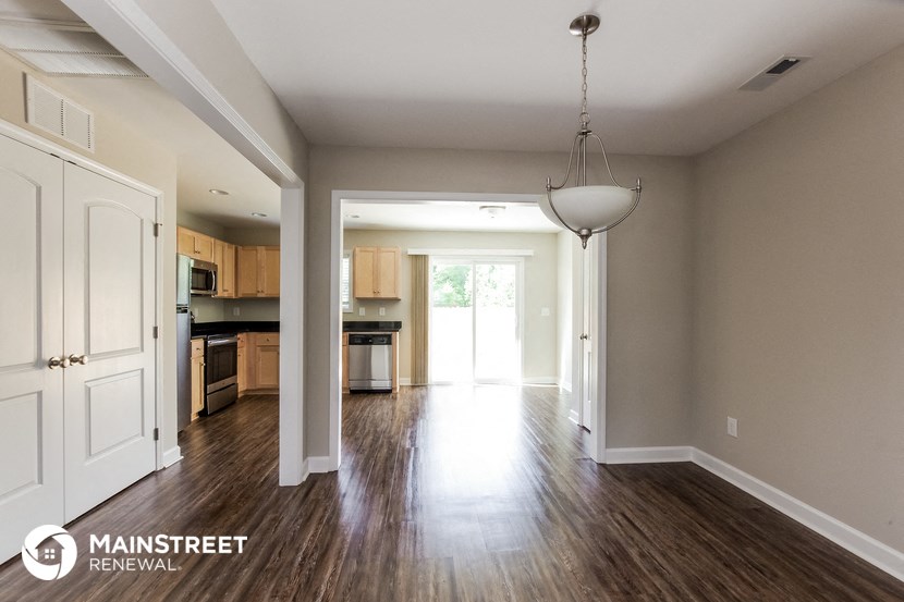 an empty living room and kitchen with wood flooring