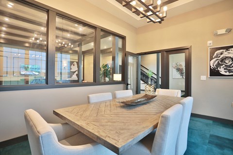 A dining room with a large table and chairs.