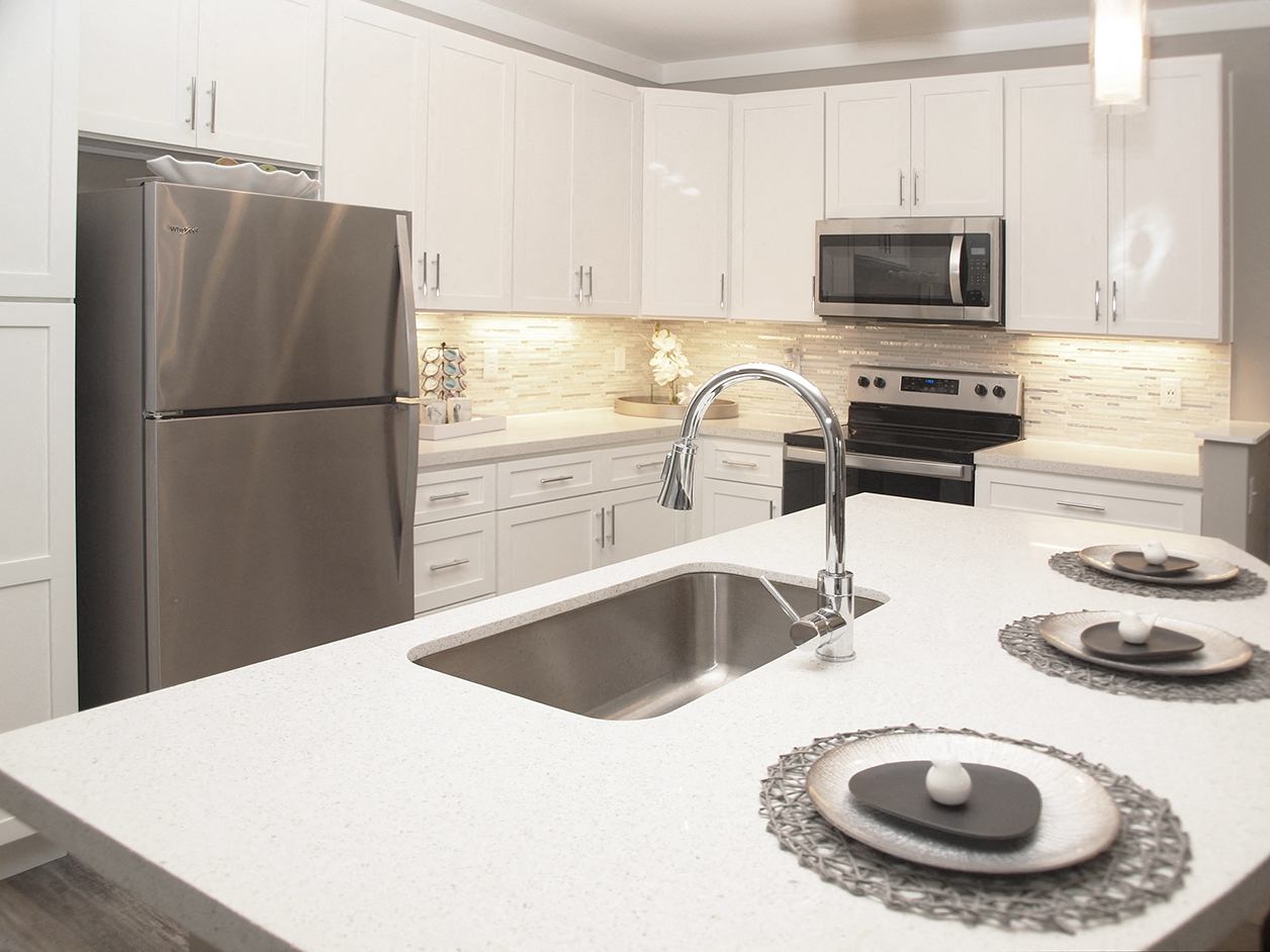 a white kitchen with stainless steel appliances and a sink
