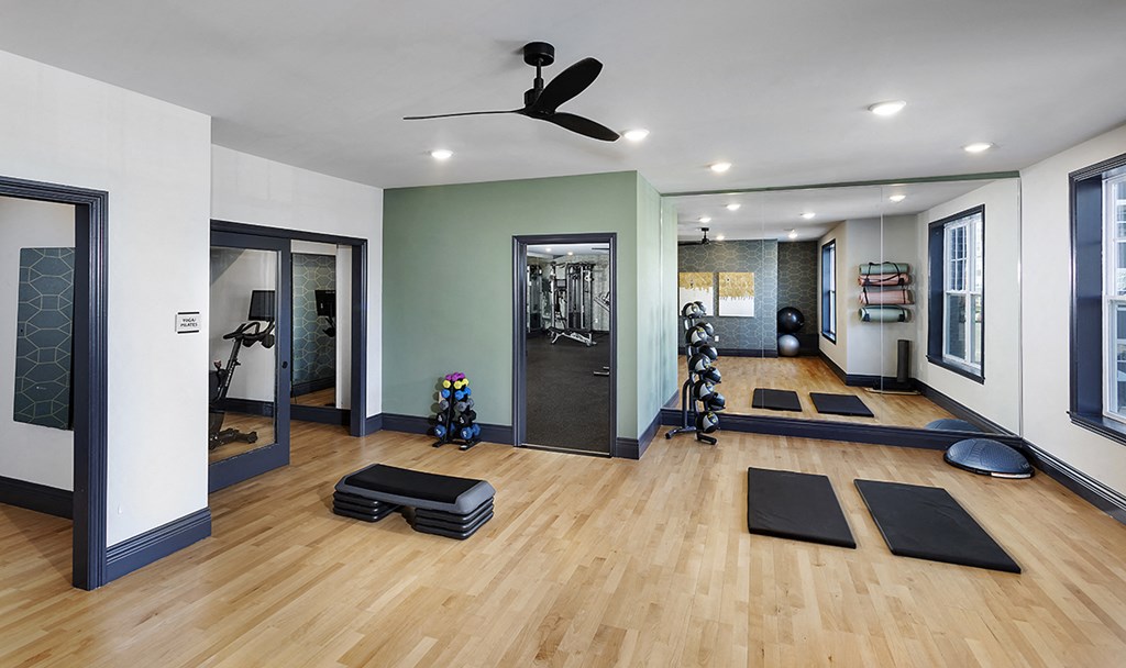 a yoga room with yoga mats and a ceiling fan
