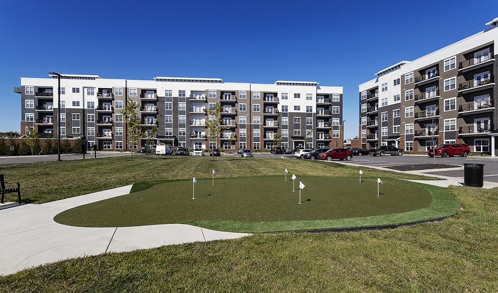 a small grassy area with an apartment building in the background