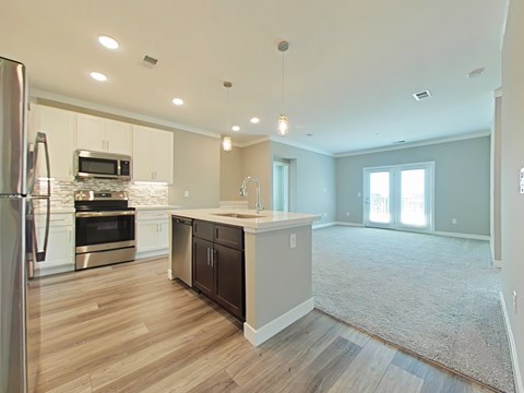 A kitchen with a refrigerator, microwave, oven, and sink.