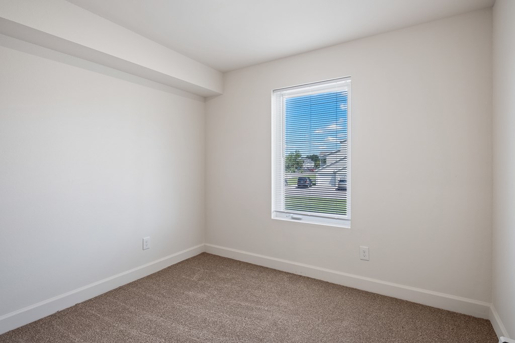 A room with a window and carpeted floor.