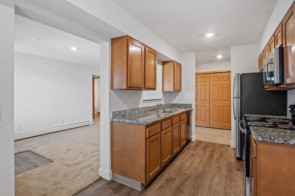 A kitchen with brown cabinets and a granite countertop.