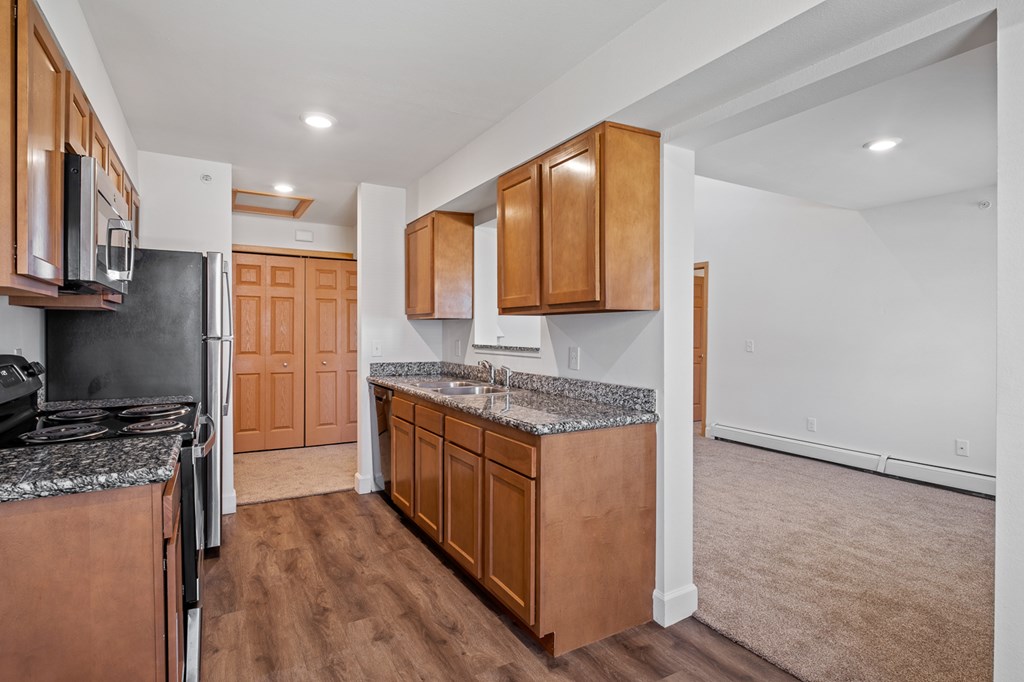 A kitchen with wooden cabinets and a black countertop.