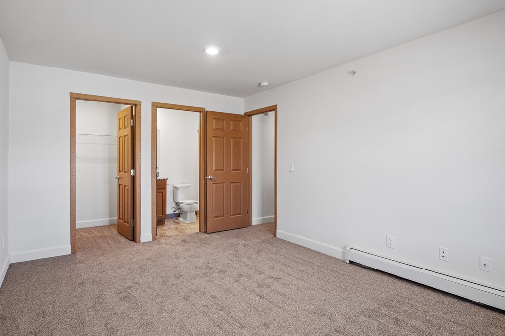 A room with a carpeted floor and a toilet in the corner.