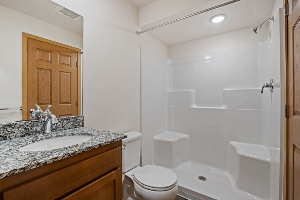A white bathroom with a toilet, sink, and shower.