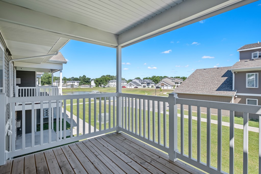 A white deck with a white railing and a white house.
