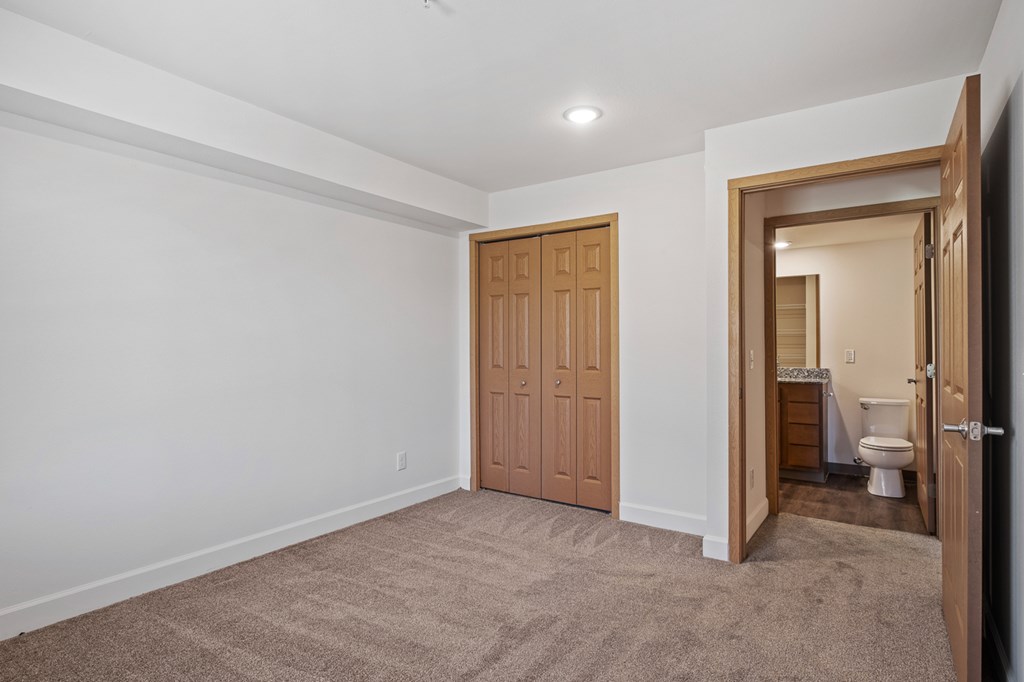 A room with a carpeted floor and a toilet in the doorway.