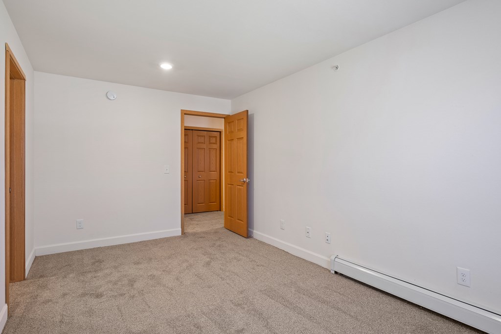 A room with a carpeted floor and a wooden door.