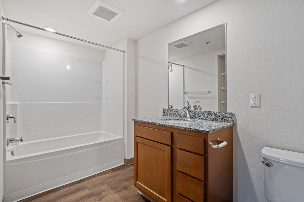 A bathroom with a wooden vanity and a walk-in shower.