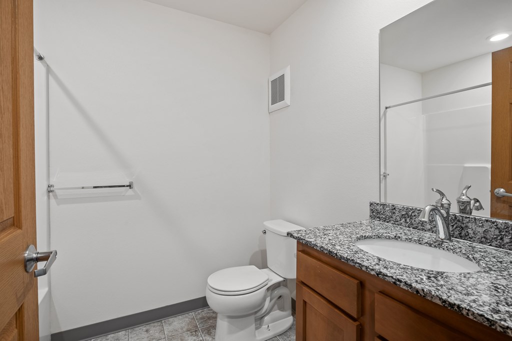 A white toilet sits in a bathroom next to a sink.