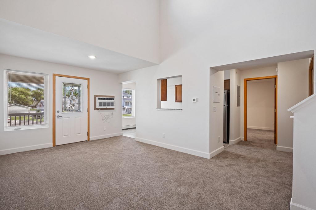 A spacious room with a carpeted floor and white walls.