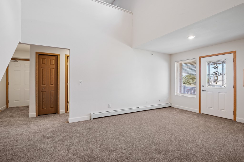 A room with a brown door and a window with a view of trees.