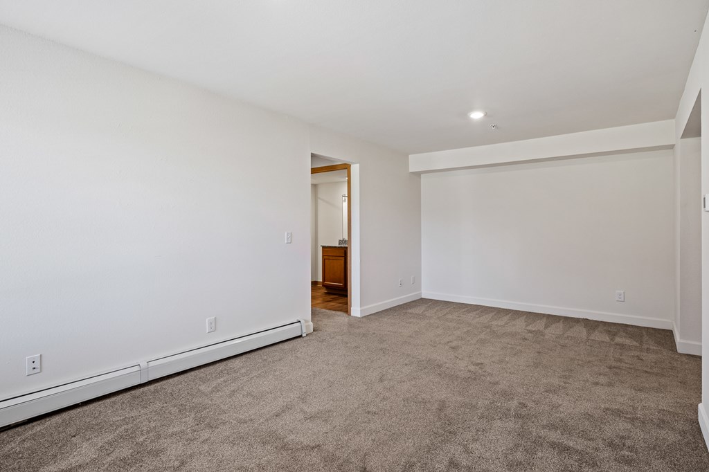 A spacious room with a carpeted floor and white walls.